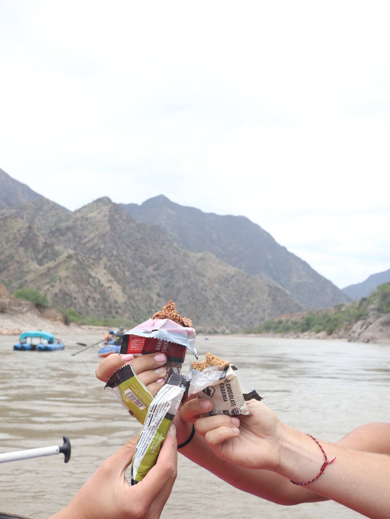 hands holding Kate's Real Food bars on a river