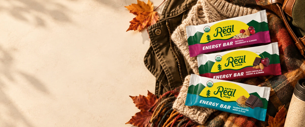 Kate's Real Food Energy Bars in Oatmeal Cranberry & Almond, Dark Chocolate Cherry & Almond and Peanut Butter Hemp & Flax on a cozy sweater, plaid scarf and autumn leaves