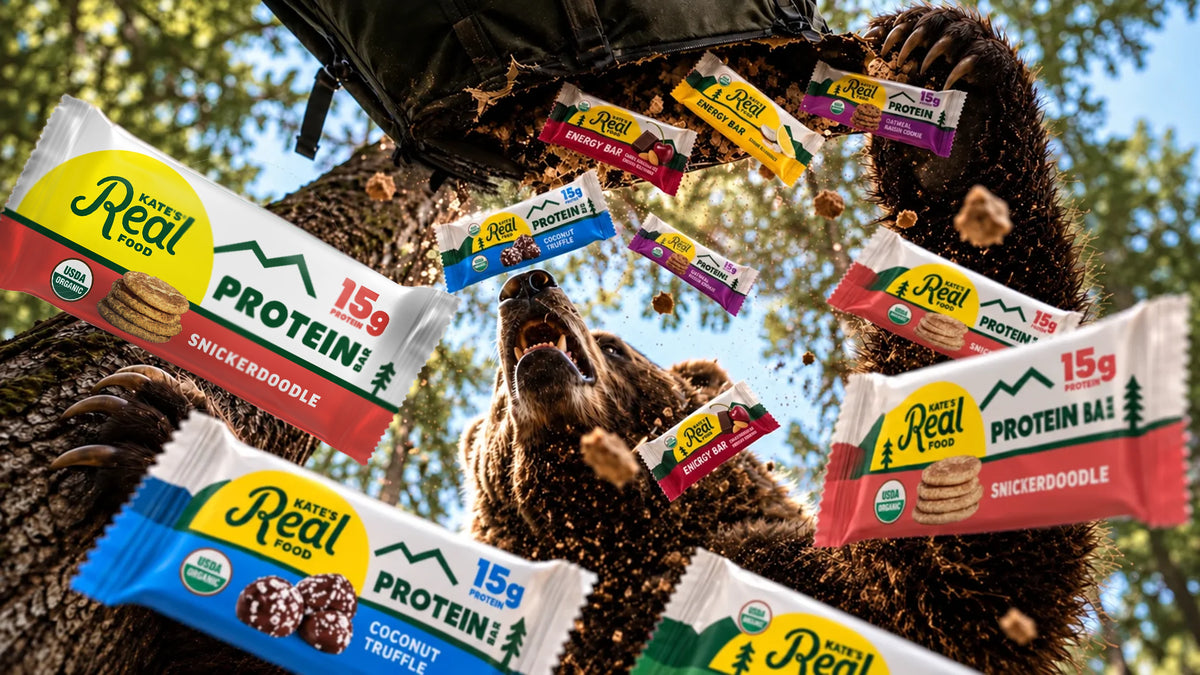 A bear looks up as Kate's Real Food protein and energy bars tumble out of a torn backpack