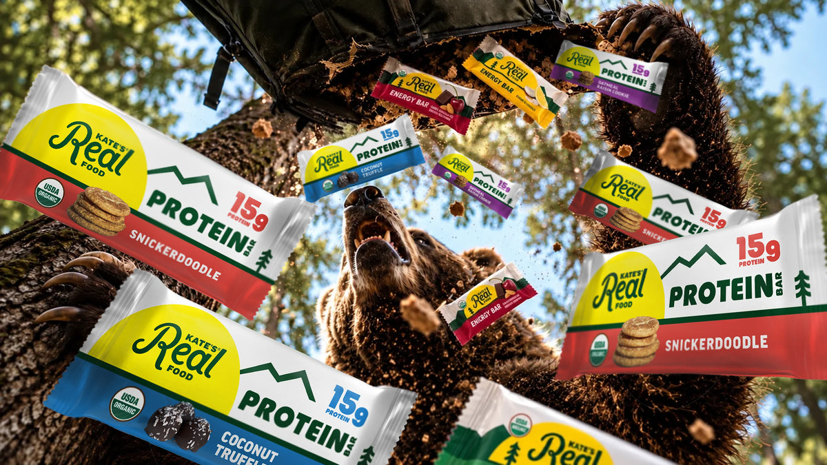 A bear looks up as Kate's Real Food protein and energy bars tumble out of a torn backpack